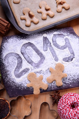 2019 inscription on a flour sprinkled board, gingerbread men cut out of shortbread dough are ready to be baked