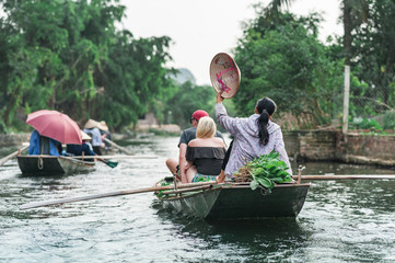 Fototapeta na wymiar Boat ride from Vung Tram Pier. Traditional paddle-boat trip lets the tourists truly appreciate the serenity and beauty of nature along the Ngo Dong River. The grottoes and limestone karsts of Tam Coc.