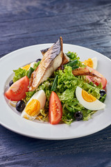 A modern variation of Caesar salad. Fish salad with eggs and vegetables. A piece of meat and fish is grilled to a tasty crust. Fresh juicy cucumbers, tomatoes, lettuce, greens and asparagus.