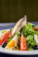 A modern variation of Caesar salad. Fish salad with eggs and vegetables. A piece of meat and fish is grilled to a tasty crust. Fresh juicy cucumbers, tomatoes, lettuce, greens and asparagus.