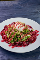 An unusual modern low-calorie salad. A ball of ultramodern salted ice cream for a salad from molecular cuisine. Appetizer from greens, beets, sauce, goat cheese, poached eggs and nuts.