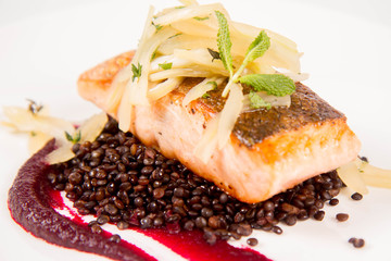 Baked salmon, beetroot mousse, black lentils and pear on a white background