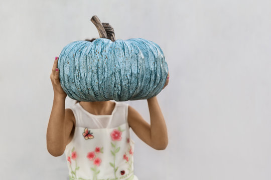 A Little Girl Holding Blue Pumpkin Infront Of Her Face