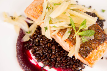 Baked salmon, beetroot mousse, black lentils and pear on a white background