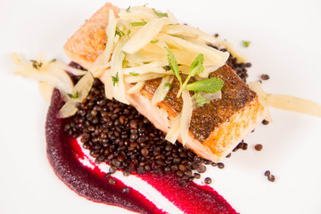 Baked salmon, beetroot mousse, black lentils and pear on a white background