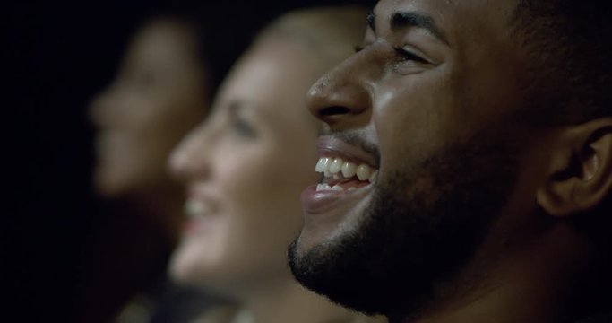 Extreme close up of a movie theatre audience laughing and enjoying a movie.
