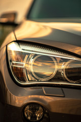 Headlights and hood of sport brown car