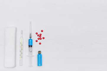 Syringe, bandage, pills, thermometer and ampoule with blue liquid drug on the doctor table. Medical...
