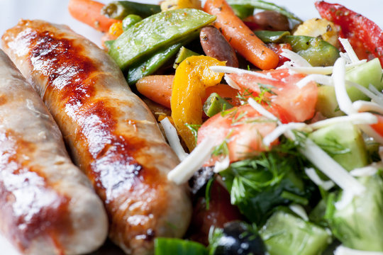 Macro of sausages and fried vegetables from side very closeup image