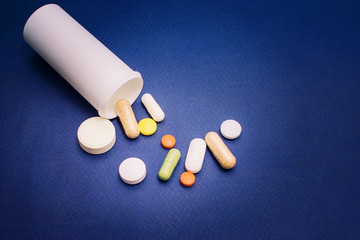 Tablets from a vial on a blue background