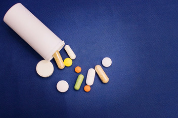 Tablets from a vial on a blue background
