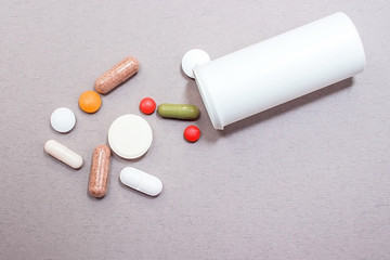 Tablets and pills from a bottle on a gray background