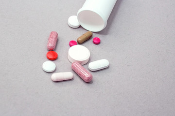 Tablets and pills from a bottle on a gray background