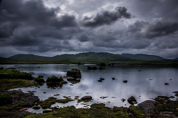 Landscape view of blue lake and dark cloudy sky above.Ireland.
