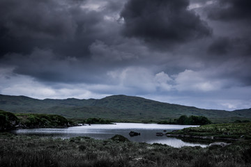 Landscape view of blue lake and dark cloudy sky above.Ireland.