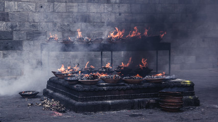 Close up view of many sacred flames burning in a platter, standing on a table. Preparation for burial ceremony. Pashupatinath Temple, Kathmandu, Nepal.