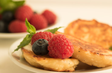 Close-up: Fresh berries of raspberries and blueberries are on delicious pancakes with cottage cheese.