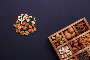 Assortment of nuts in a wooden box on a black background - healthy snack.