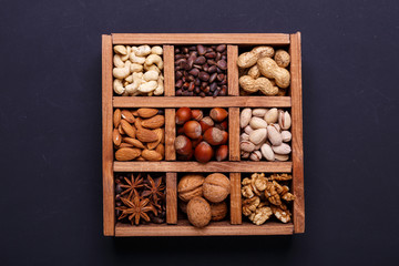 Assortment of nuts in a wooden box on a black background - healthy snack.