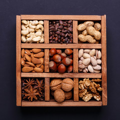 Assortment of nuts in a wooden box on a black background - healthy snack.