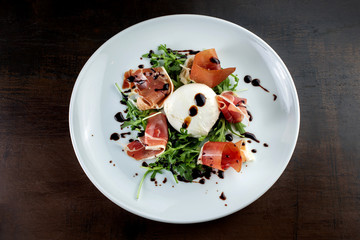 Salad with bacon and soft cheese. It is decorated with sauce.