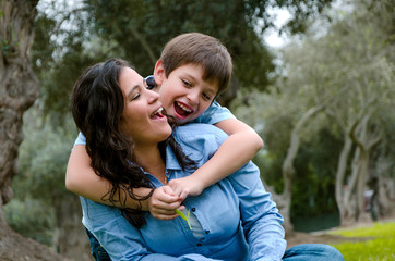 Child hugging his mother smiling on an autumn afternoon