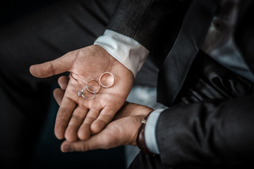 Groom holding wedding rings on the palm, the groom in a blue suit, groom holding wedding rings, groom's hand holding a ring, wedding ring in groom hand