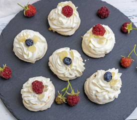 round meringues with whipped cream on a black graphite board