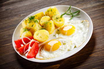 Fried eggs, boiled potatoes and vegetables