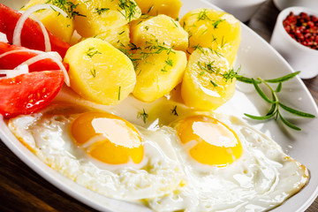 Fried eggs, boiled potatoes and vegetables