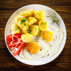 Fried eggs, boiled potatoes and vegetables