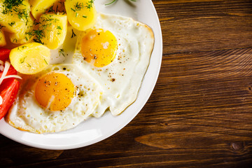 Fried eggs, boiled potatoes and vegetables