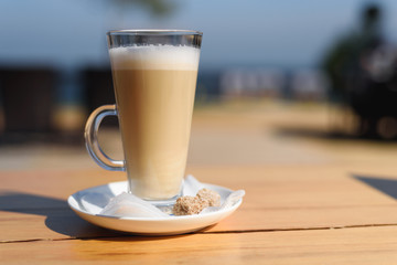 Glass Cup with hot latte on wooden table on summer terrace cafe
