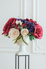 Shot of tender magnificent bouquet of roses on flower stand against white background in banquet hall used as decoration. Wedding flowers