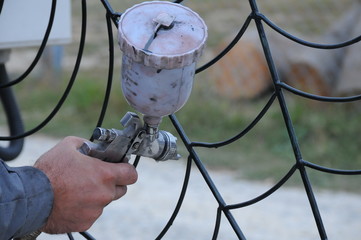 Varnishing fence with paint sprayer