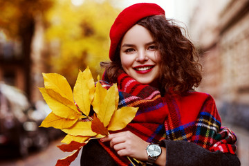 Outdoor close up portrait of young beautiful happy smiling girl wearing stylish red beret, tartan...