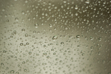 raindrops on window glass on background of cloudy sky