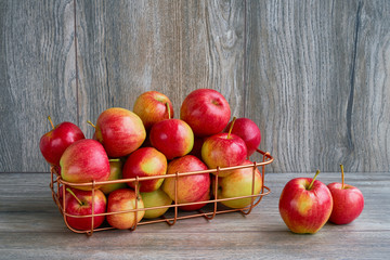 Red apples in basket on wooden background. Copy space