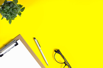 Creative workspace desk on bright yellow background.