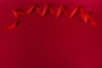 Wavy polka dot red ribbon on red background.
