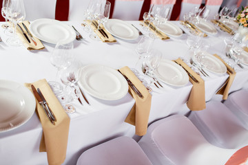 Table at a luxury wedding reception. Beautiful flowers on the table. Serving dishes, glass glasses, waiters work,