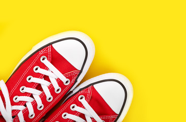 New red sneakers on yellow background with copy space. Youth shoes. Keds.