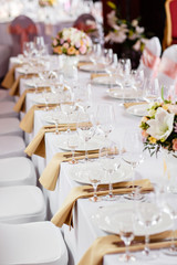 Table at a luxury wedding reception. Beautiful flowers on the table. Serving dishes, glass glasses, waiters work,