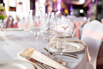 Round table at a luxury wedding reception. Beautiful flowers on the table. Serving dishes, glass glasses, waiters work,