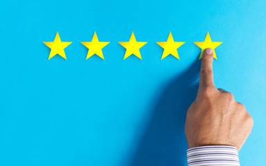 Hand choosing 5 stars rating on blue background