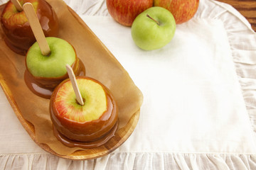 Three Hand Dipped Homemade Caramel Apples on a White Tablecloth