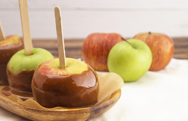 Three Hand Dipped Homemade Caramel Apples on a White Tablecloth