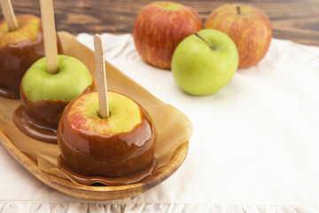 Three Hand Dipped Homemade Caramel Apples on a White Tablecloth