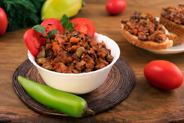Vegetable stew of courgettes, eggplant, onions, carrots and tomatoes in a white bowl, fresh bitter pepper and whole tomatoes.