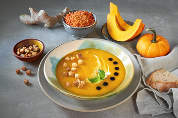 Tasty pumpkin cream soup served with croutons, cream and balsamic vinegar in ceramic bowl